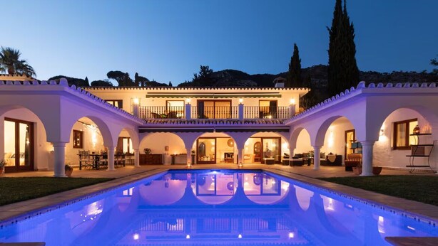 A large pool with a reflection, a building with arches, and a balcony.