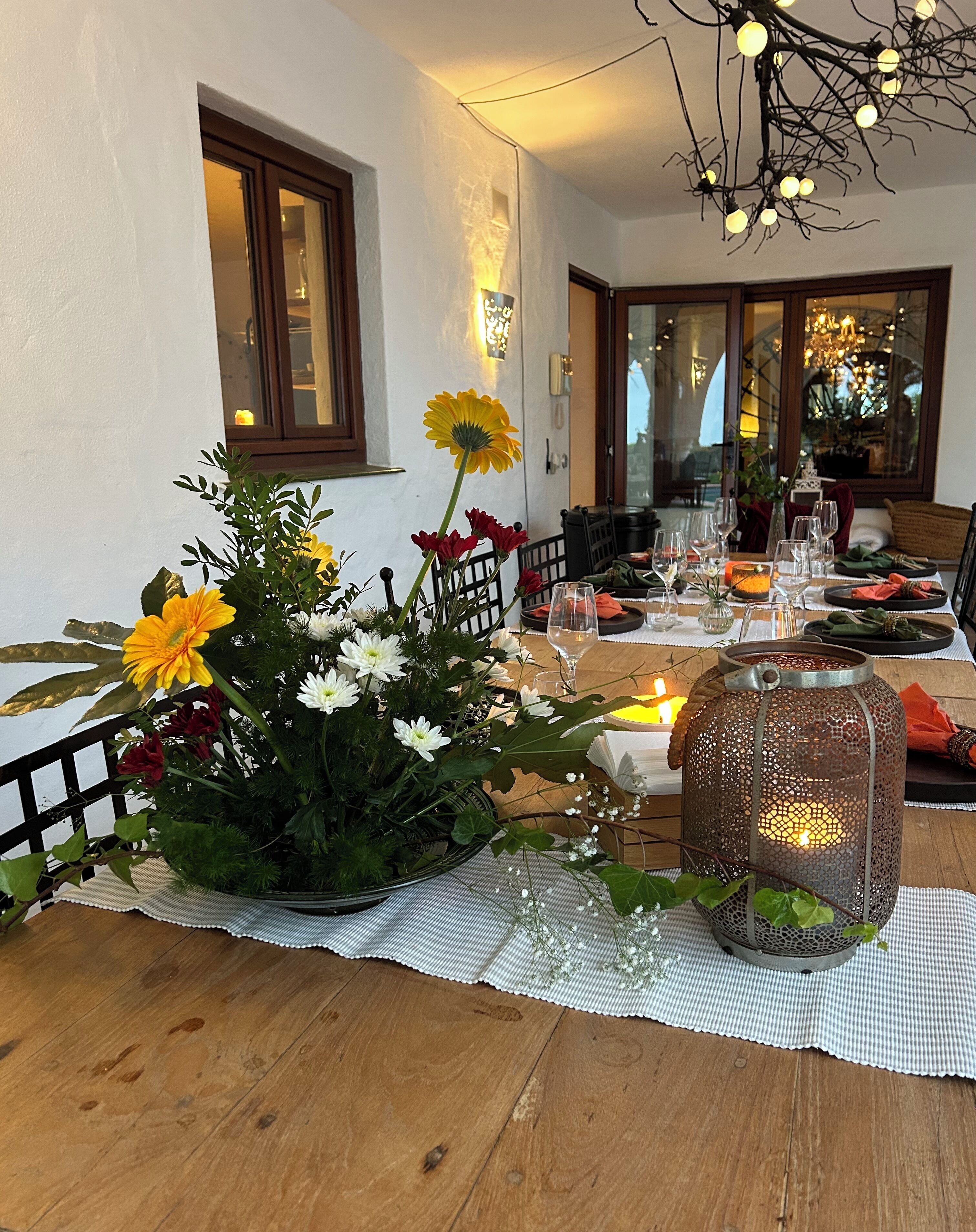 Une table à manger décorée de fleurs, de bougies et d’une lanterne.