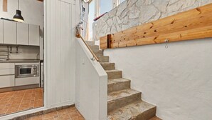 A kitchen with a microwave, a wooden staircase, and a stone wall. - Vacation Home 'Atlantic Dream' with Sea View, Private Terrace and Wi-Fi (Costa Calma)