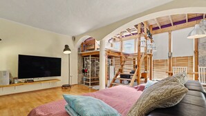 A cozy bedroom with a bed, pillows, a TV, wooden flooring, and a loft area with a staircase. - Vacation Home 'Atlantic Dream' with Sea View, Private Terrace and Wi-Fi (Costa Calma)