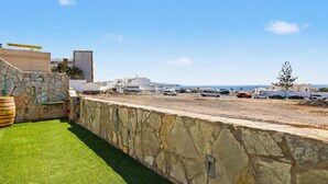 A parking lot with a stone wall and a grassy area. - Vacation Home 'Atlantic Dream' with Sea View, Private Terrace and Wi-Fi (Costa Calma)