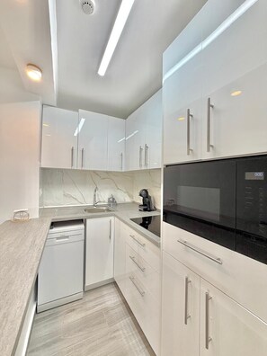 A modern kitchen with white cabinetry, a black refrigerator, and a built-in dishwasher. - TERRASOL TRINIDAD APARTMENT (Torre del Mar)