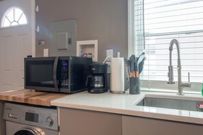 Eine Küche mit Mikrowelle, Kaffeemaschine und Spüle.