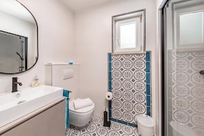 A bathroom with a white sink, a mirror, a toilet, and a shower area. - Beachside Villa Mia Apartments (Lovran)