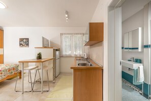 Eine kleine Küche mit Essbereich, einem Kühlschrank und einem Fenster mit Vorhängen.