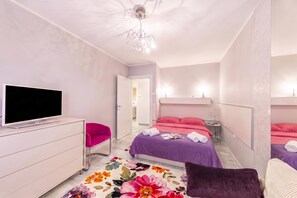 Een moderne slaapkamer met een flatscreen televisie, een kleurrijk bloemenkleed en een groot bed met een paars sprei.