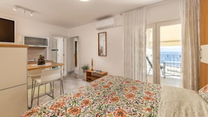 Quarto de hotel com uma cama, escrivaninha, cadeira, mesa pequena, espelho e varanda com vista.