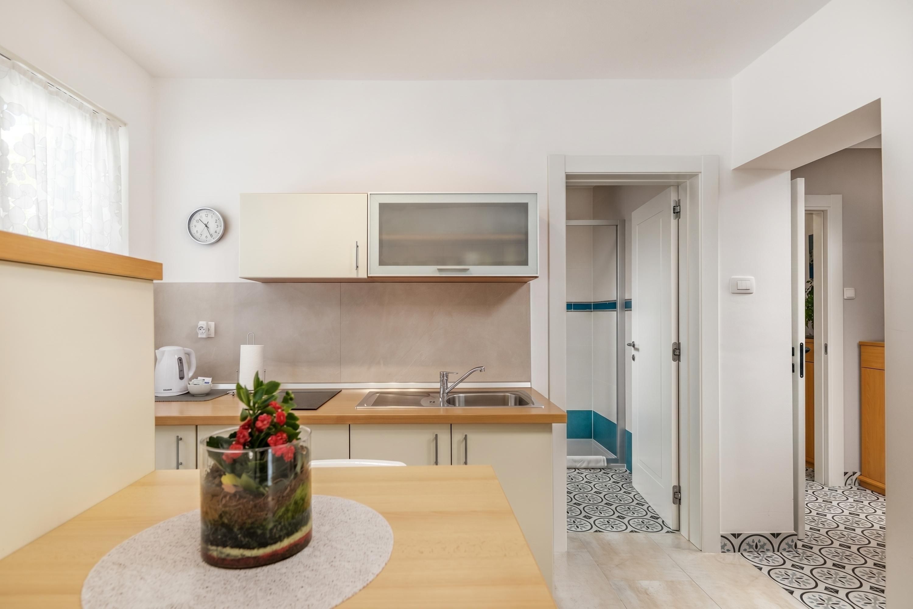 A modern kitchen with a sink, cabinets, and a clock on the wall.