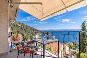 A balcony with a table set for two, overlooking a coastal view. - Beachside Villa Mia Apartments (Lovran)