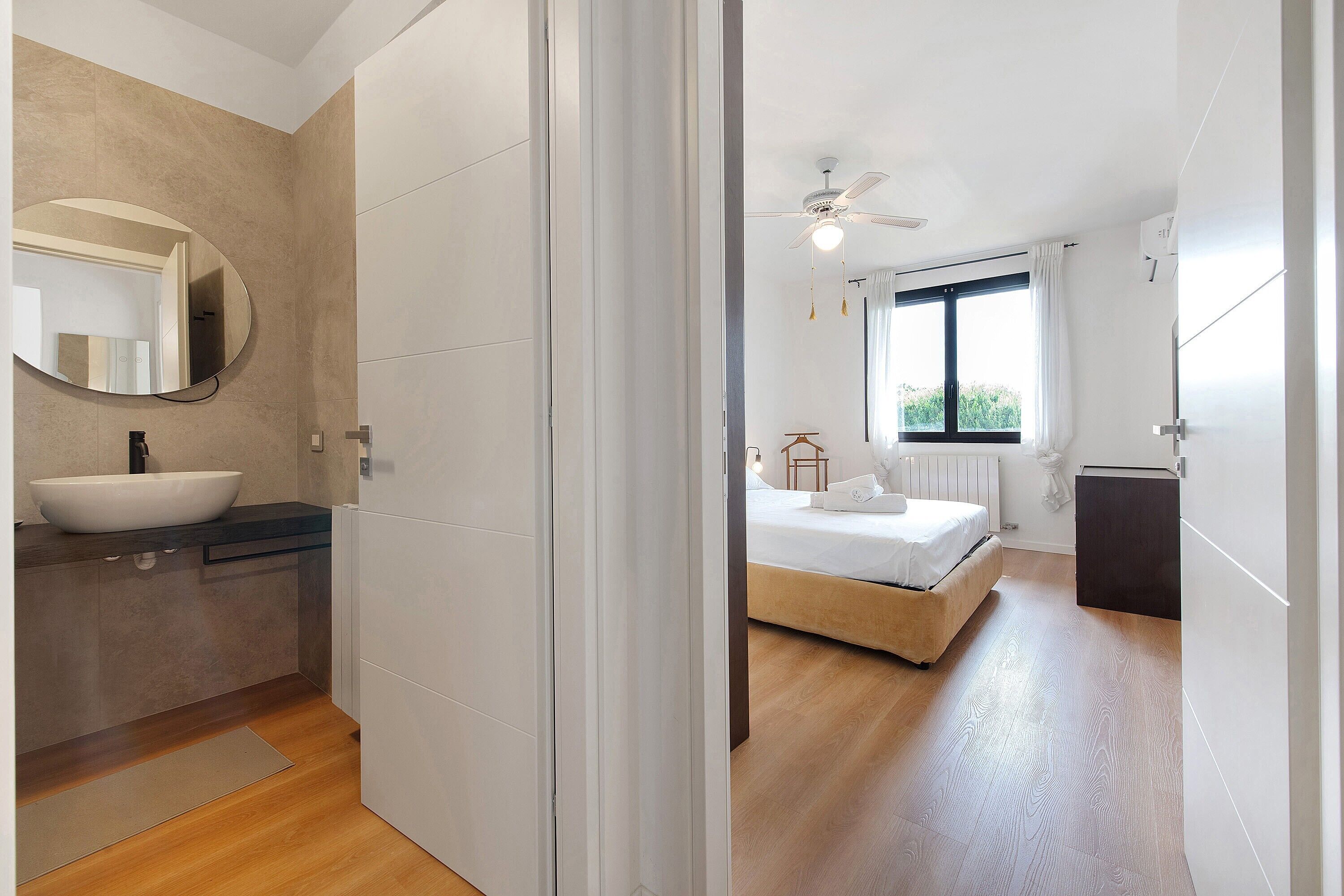 A modern bedroom with a bed, a window, and a ceiling fan.