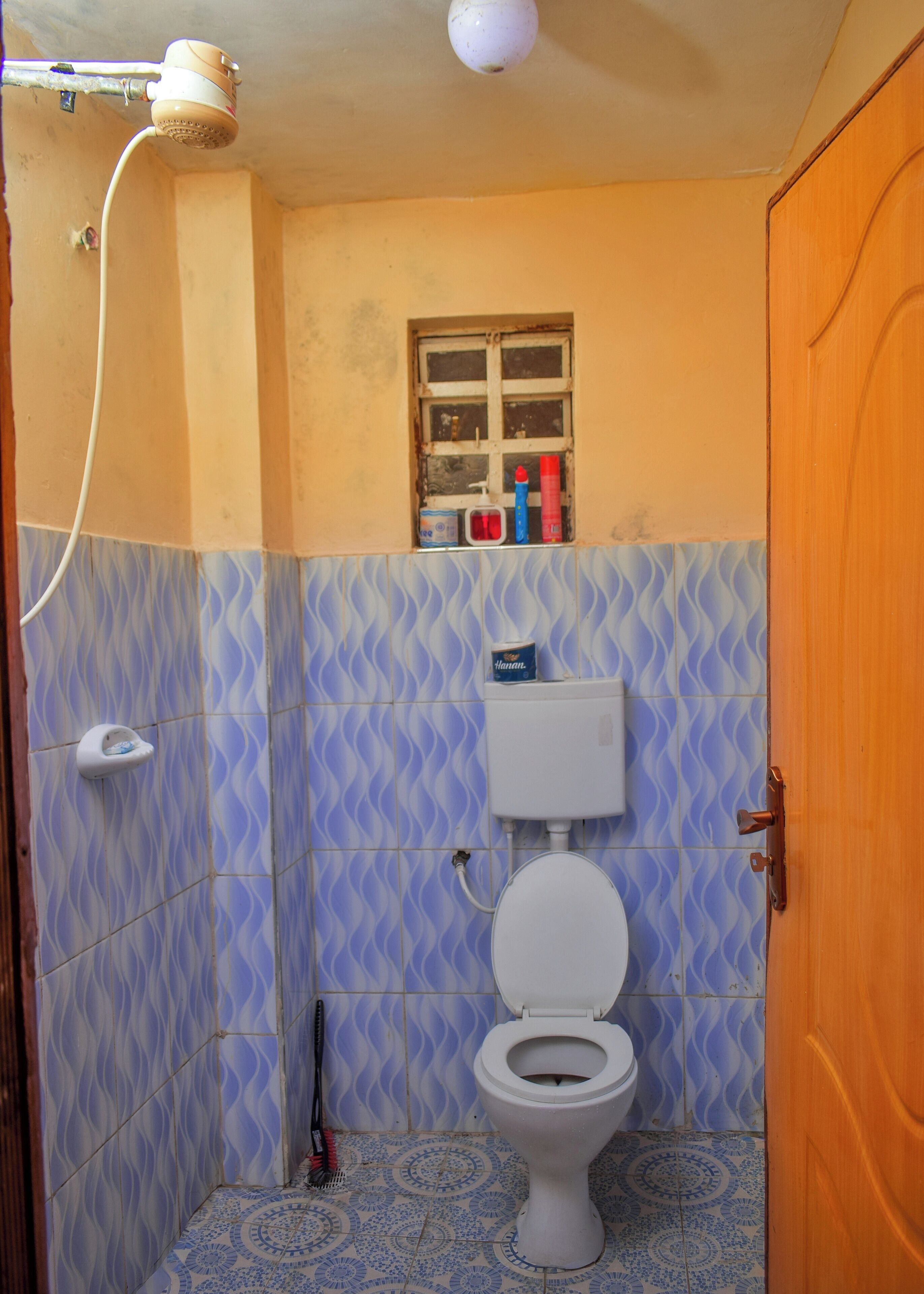 A small bathroom with a toilet, a window, and a shower.
