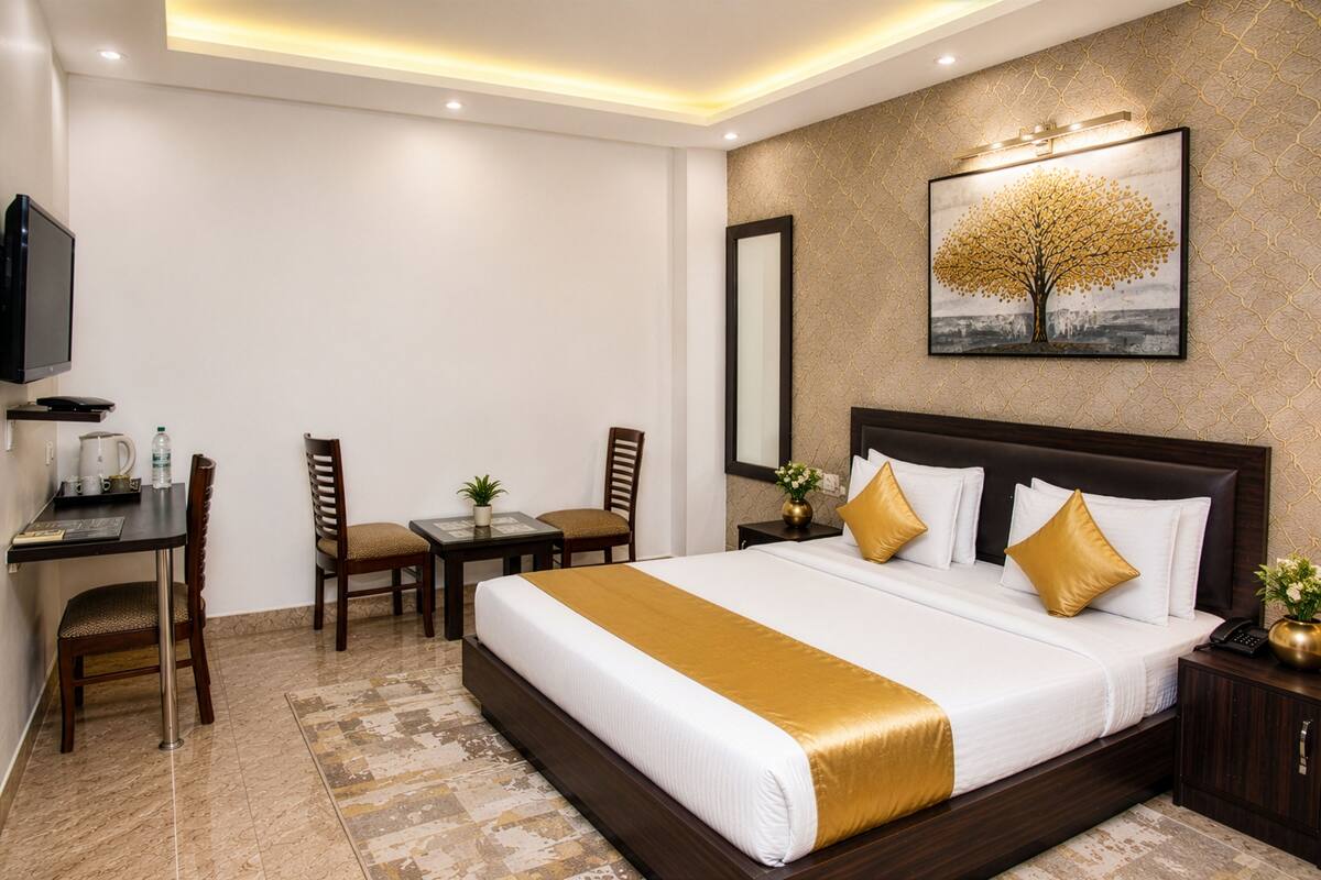 Habitación de hotel con una cama grande, un escritorio con silla, televisor y un cuadro en la pared.