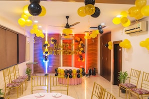 Una habitación con ventilador de techo, aire acondicionado de pared y una decoración con globos que dice 'HAPPY BIRTHDAY'.