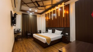 Habitación de hotel con cama, mesita de noche, silla, escritorio y televisor montado en la pared.