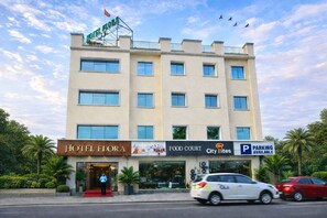 Ein Hotel mit einem Schild, das 'HOTEL FLORA' zeigt, einer Food Court und einem Parkplatzschild.