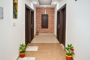 Un pasillo con pared de ladrillo, puertas de madera y plantas en macetas.