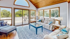 A spacious living room with a high ceiling, large windows, and a view of the outdoors. - 🌊 OBX Escape w/ Pool, Hot Tub & Volleyball Court — Pet Friendly 🐶 (Southern Shores)
