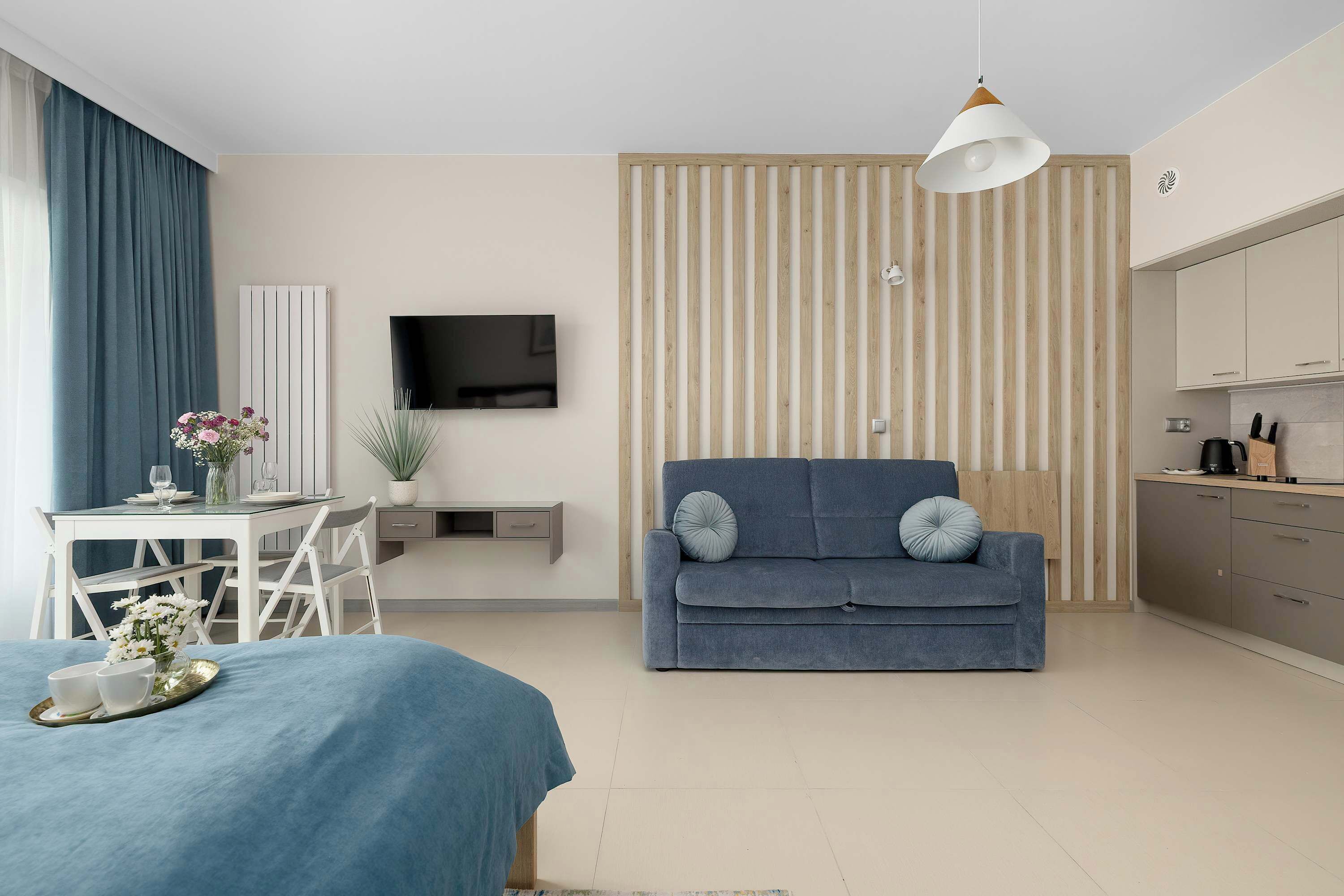 Een moderne woonkamer met een bank, een televisie, een eettafel met stoelen en een keukenhoek.
