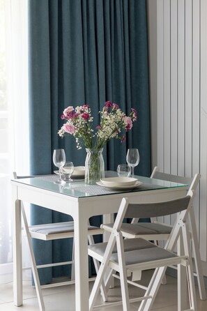 Une table à manger avec des chaises, un vase de fleurs et des verres à vin.