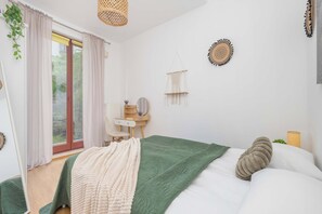 Ein Schlafzimmer mit Bett, Schminktisch, Spiegel und einem Fenster mit Vorhängen.