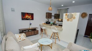 Una sala de estar moderna con un sofá, una mesa de centro y un televisor que muestra una chimenea.
