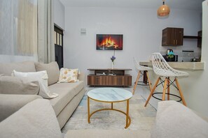 Ein Wohnzimmer mit einer Couch, einem Couchtisch und einem an der Wand montierten Fernseher.