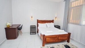 Una habitación de hotel con una cama de madera, mesitas de noche, un escritorio y una silla.
