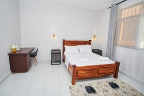 Ein Hotelzimmer mit einem Holzbett, Nachttischen, einem Schreibtisch und einem Stuhl.