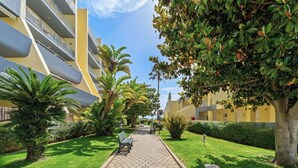 Un sentiero alberato con una panchina e un edificio con balconi.