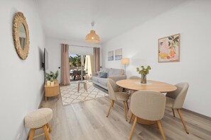 Ein modernes Wohnzimmer mit einem runden Esstisch, einer Couch, einem Fernseher und einem großen Spiegel.