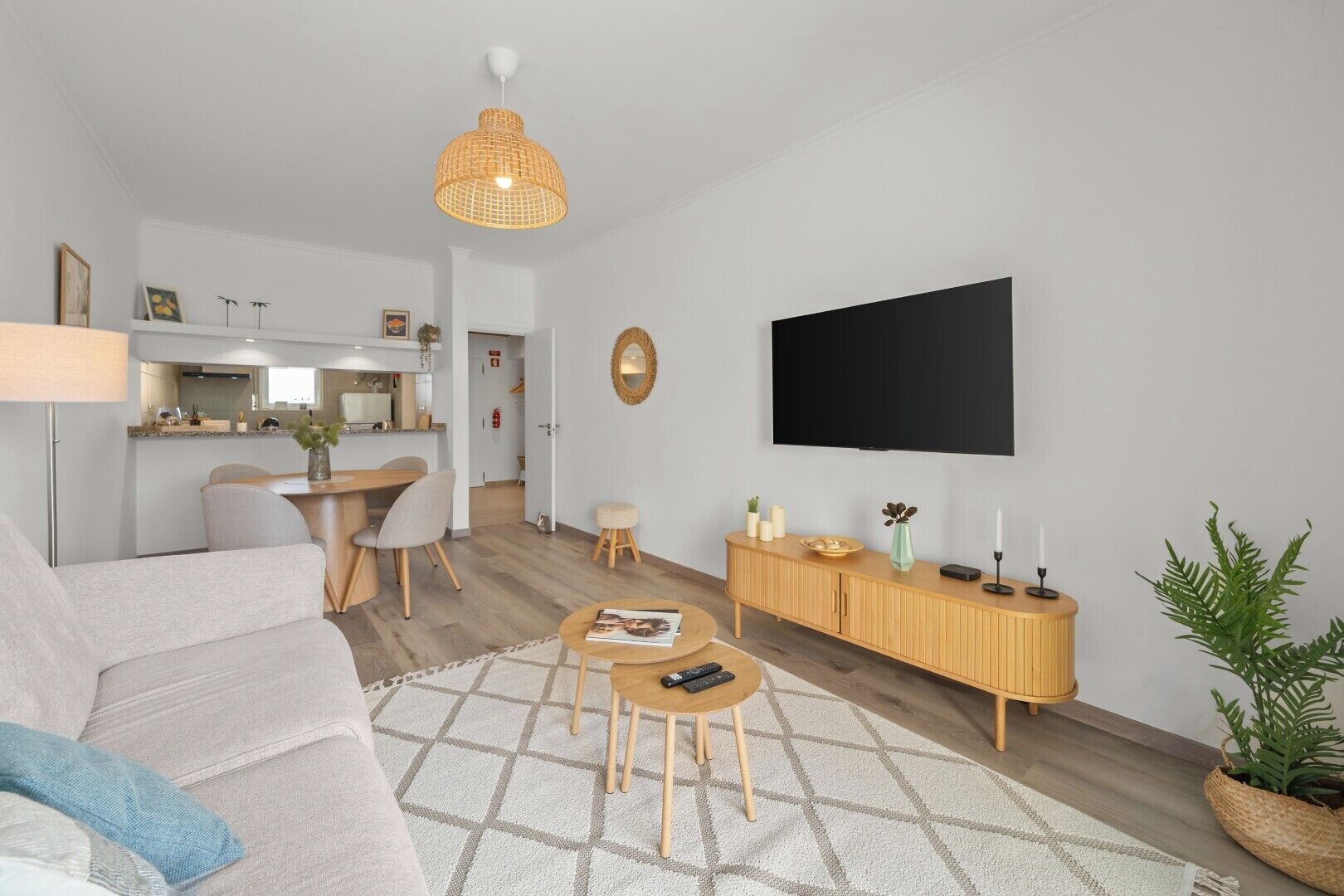 Een moderne woonkamer met een bank, salontafel, televisie en een eethoek met stoelen en een kleine tafel.