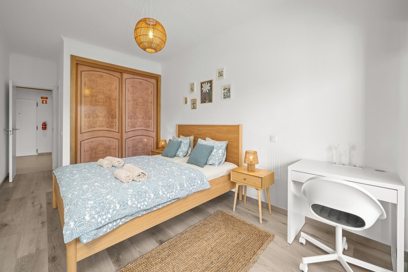 A bedroom with a bed, bedside tables, a desk, and a chair.