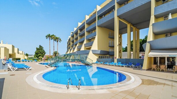 Un hotel con piscina, diversi balconi e un ristorante.