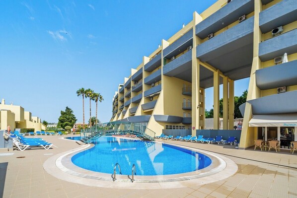 Ein Hotel mit Schwimmbad, mehreren Balkonen und einem Restaurant.