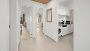 Una cucina moderna con mobili bianchi, un forno a microonde e una lavatrice.