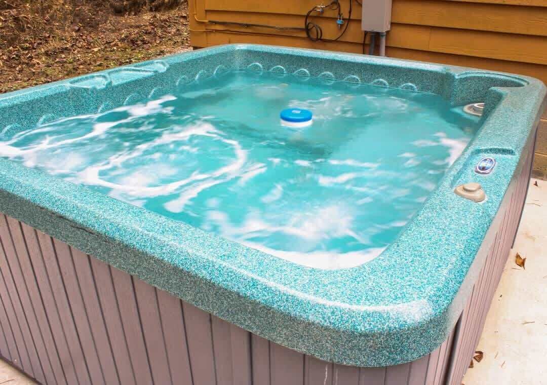 A hot tub with a blue lid, surrounded by a wooden deck.