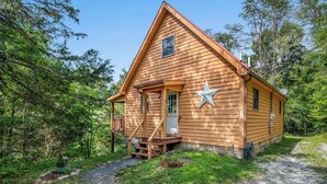 Una casetta in legno con veranda, decorazione a stella e una piccola finestra.