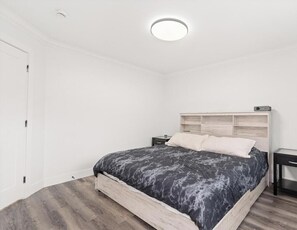 Ein Schlafzimmer mit einem Bett, Nachttischen, einer Nachttischlampe und einer Deckenleuchte.