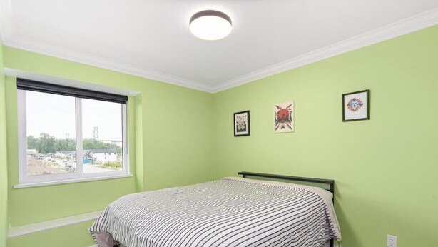 A bedroom with a bed, a window, and three framed pictures on the wall. - Modern 5BR Home Near Lions Gate | Glass Deck + BBQ (West Vancouver)