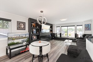 Ett modernt vardagsrum med en platt-TV, ett runt matbord och en soffa.