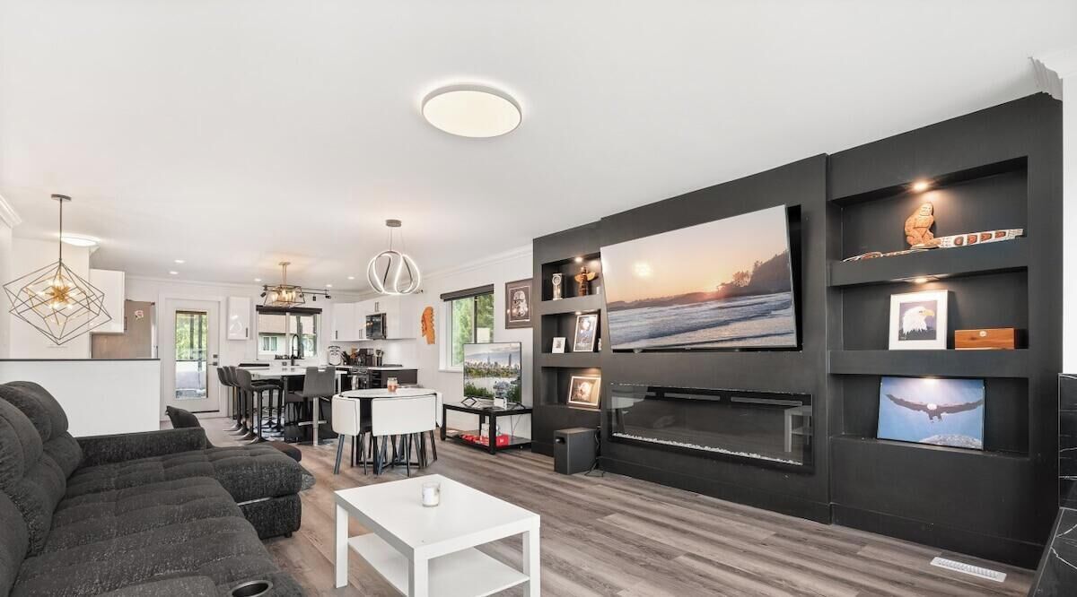 A modern living room with a large flat-screen TV, a fireplace, and a dining area with a bar.