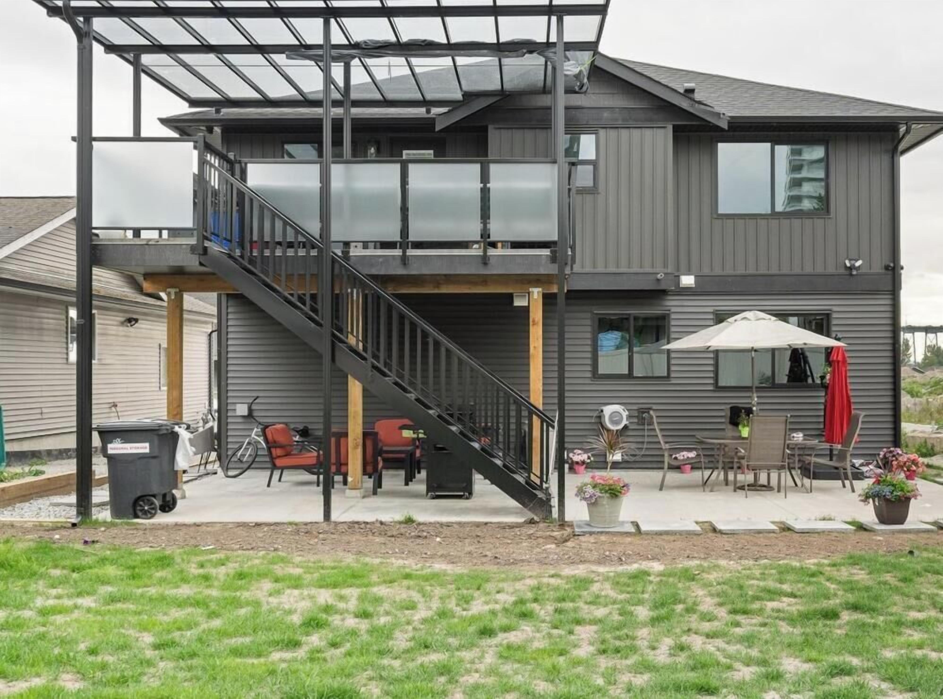 A two-story house with a covered outdoor area, a staircase, and outdoor furniture.