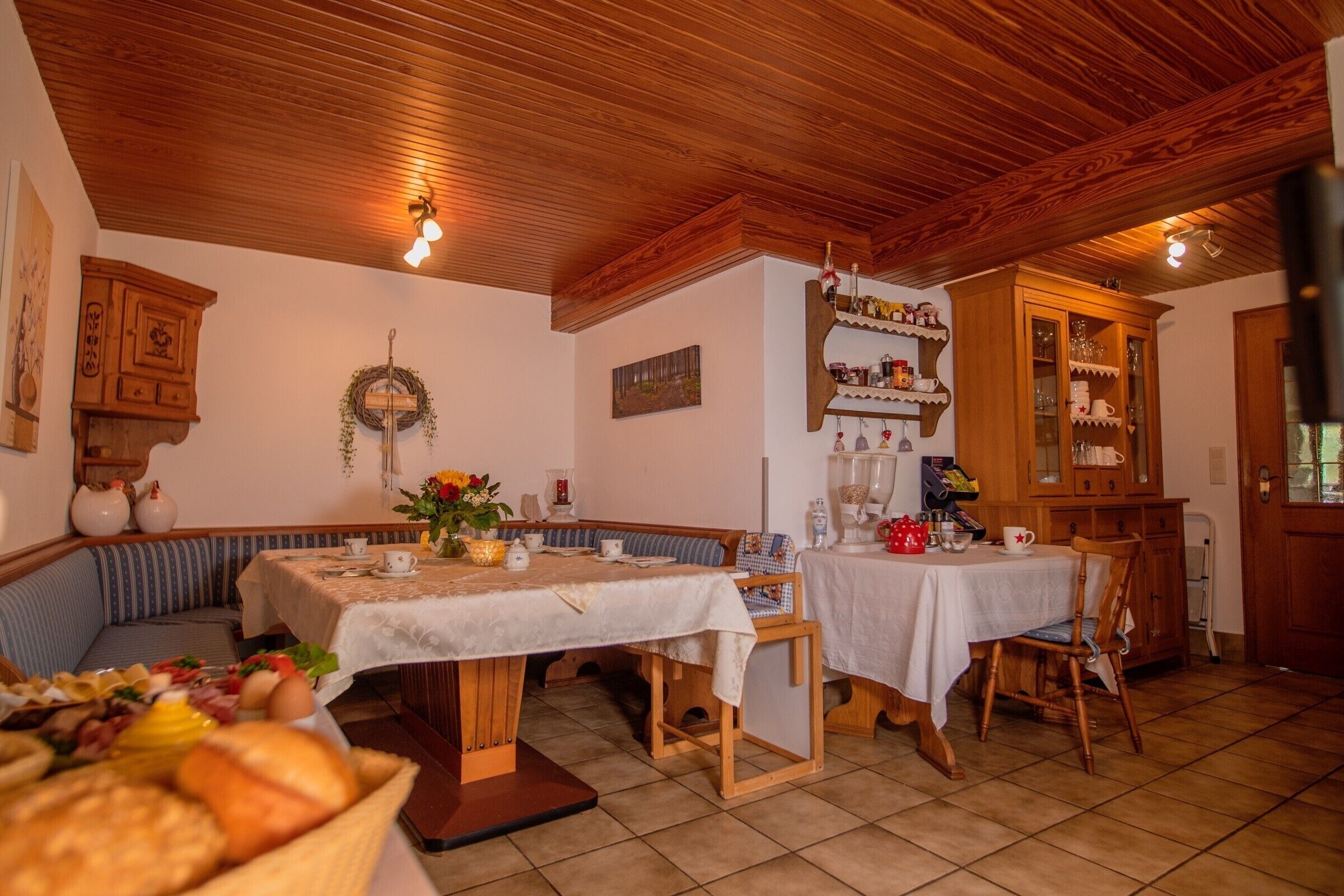 Un coin repas chaleureux, avec des meubles en bois, une table mise pour le petit-déjeuner et une guirlande décorative accrochée au mur.