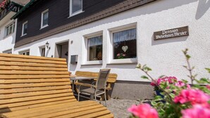 Een traditioneel gebouw met een bord waarop 'Pension Dietelhaus Meister' staat, terras en een pad van stenen.