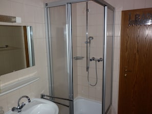 Ein Badezimmer mit Duschkabine, Waschbecken und Spiegel.