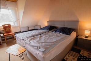 Un dormitorio con cama, mesita de noche, silla y radiador.