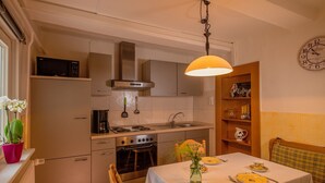 A kitchen with a stove, oven, microwave, and a dining table set for two.