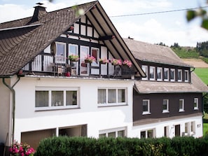 A two-story house with a balcony, large windows, and a garage.