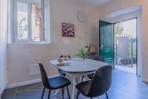 A dining area with a table, chairs, a vase with flowers, and a painting on the wall.
