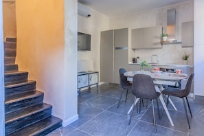 A modern kitchen with a dining area, a staircase, and a view of the living area.